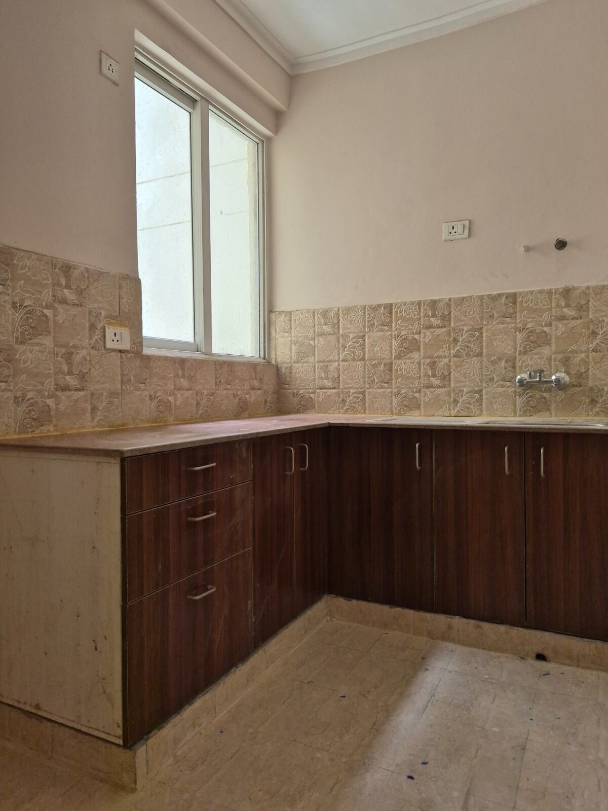 Bare civil-finish kitchen before renovation, tiled dado and unfinished counter
