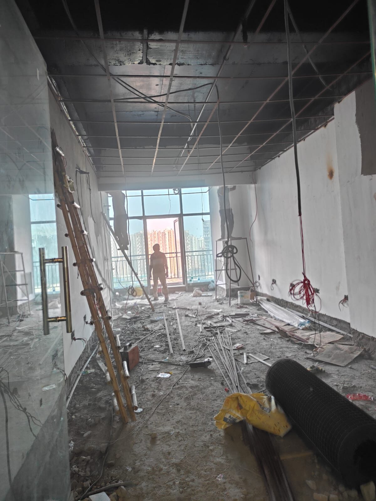 Bare concrete shell mid-construction with exposed ceiling grid and debris