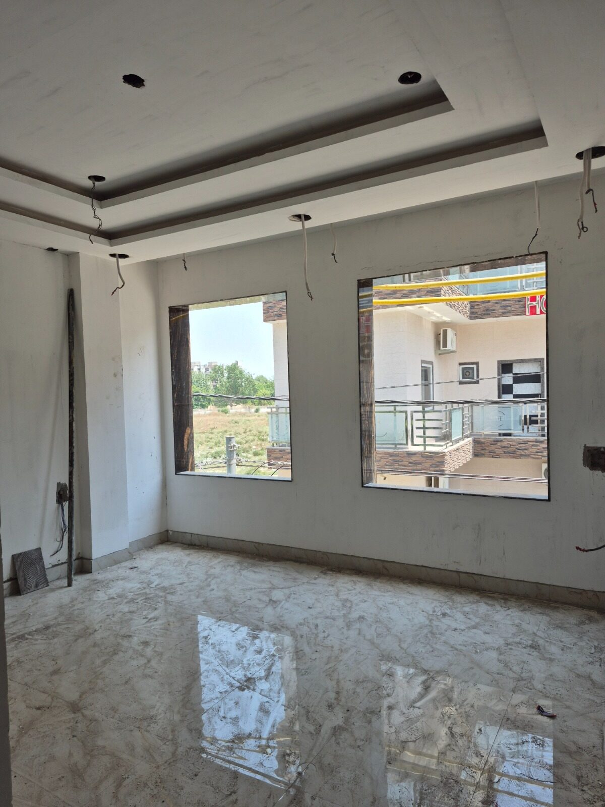 Unfinished living room with bare marble flooring and glazed window openings