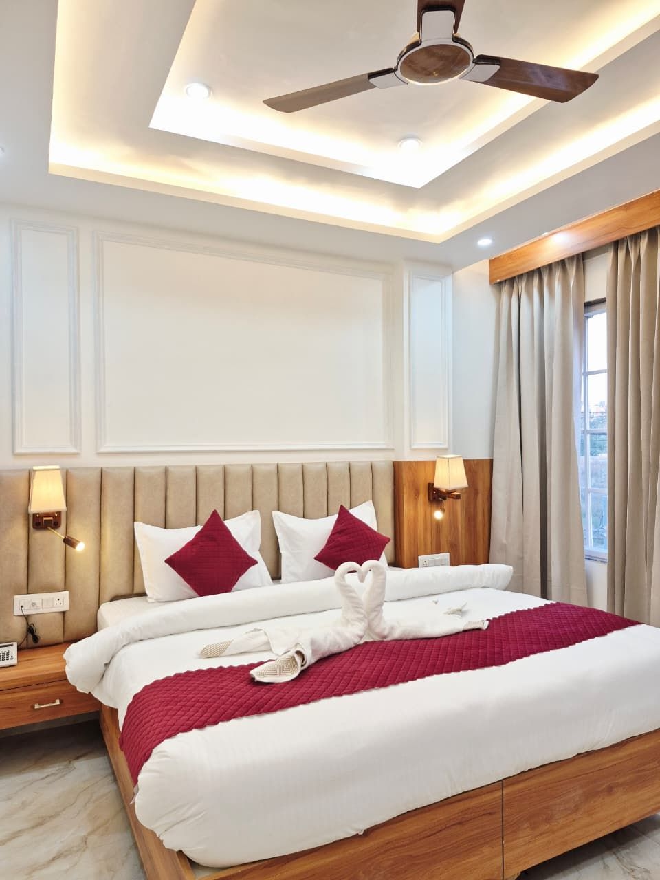 Hotel suite with an upholstered headboard, cove ceiling and bedside lighting