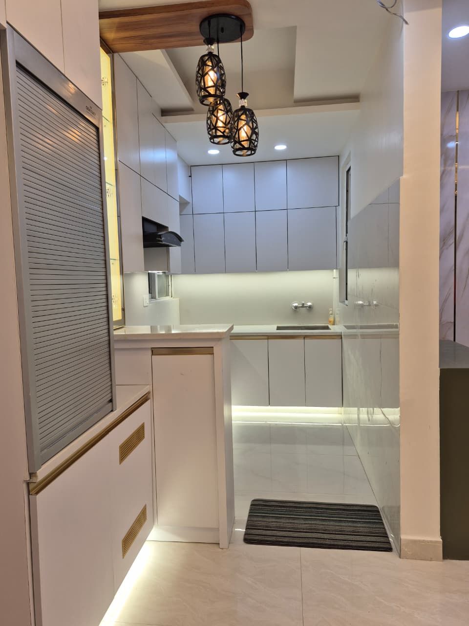 Modular kitchen with pendant lighting, breakfast counter and profile-lit shutters