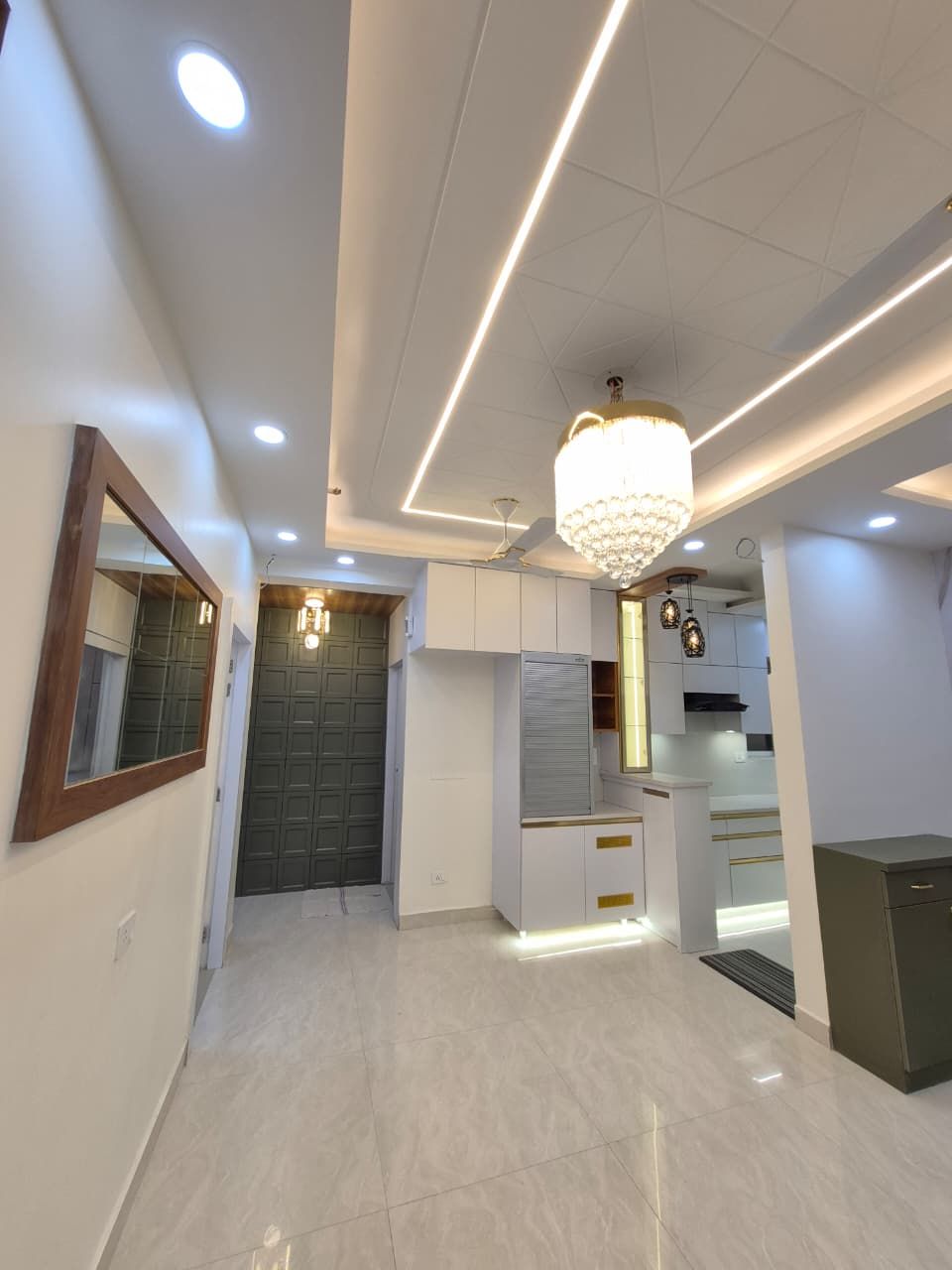 Living and dining area with panelled walls, layered false ceiling and a chandelier